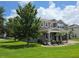 Well-maintained gray home with lush green lawn, mature trees, and inviting covered entry; showcases curb appeal at 15900 Citrus Knoll Dr, Winter Garden, FL 34787