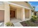Inviting front porch with decorative columns, a wood door, and well maintained garden beds at 1593 Osprey View Dr, Apopka, FL 32703