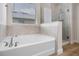 Well-lit bathroom with a soaking tub, glass shower, tile accents, and a large window at 17996 Adrift Rd, Winter Garden, FL 34787
