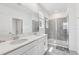 Bright main bathroom with double sink vanity, a large mirror, a glass enclosed shower, and light tile at 2345 Volunteer Ave, Kissimmee, FL 34744