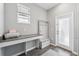 Inviting mudroom with gray desk, built-in storage bench and coat rack adjacent to the door, with modern wood-look floor tiles at 2345 Volunteer Ave, Kissimmee, FL 34744