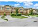 View of multiple townhomes with attached garages, green lawns, and landscaped front yards at 2508 Seven Oaks Dr, St Cloud, FL 34772