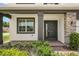 Close-up showcasing a front door with black trim, brick entrance, column, side-window, and manicured bushes at 2541 Leyland Cypress Ln, Sanford, FL 32773
