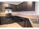 Modern kitchen features sleek, dark cabinetry, tile floors, and countertops and stainless appliances at 3569 Seneca Club Loop # 13, Orlando, FL 32808