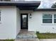 Close-up of the front entrance with a black door, lantern, and textured white siding at 4732 Luce Rd, Lakeland, FL 33813