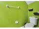 Bright bathroom with green walls, a toilet, and wall-mounted shelves, offering a clean and refreshing space at 509 Cresting Oak Cir # 73, Orlando, FL 32824