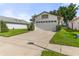 Home featuring an expansive driveway, two-car garage, and a lush green lawn at 5703 Arnold Zlotoff Dr, Orlando, FL 32821