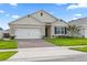 Charming single-story home featuring a well-manicured lawn, brick driveway, and an attached two-car garage at 5808 Arboretum St, St Cloud, FL 34771