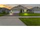 Dusk view of home with a brick driveway, well-kept lawn, and a charming facade at 5808 Arboretum St, St Cloud, FL 34771
