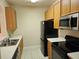 Kitchen with black appliances, light countertops, stainless steel sink, and wood cabinets at 6214 Stevenson Dr # 208, Orlando, FL 32835