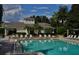 Community pool with lounge chairs and a clubhouse in a tropical landscape at 6214 Stevenson Dr # 208, Orlando, FL 32835