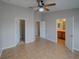 Neutral bedroom featuring tile floors, ceiling fan, and convenient access to both a bathroom and a closet at 7462 Bentonshire Ave, Windermere, FL 34786