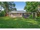 Back exterior view of the home with a screened-in porch overlooking a large grassy backyard at 815 E 11Th Ave, Mount Dora, FL 32757