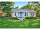 Charming single-story home with a bright blue front door, lush lawn, and covered carport at 815 E 11Th Ave, Mount Dora, FL 32757