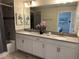 Well-lit bathroom featuring a double vanity and shower with gray tiled walls at 8934 Stinger Dr, Davenport, FL 33896