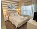 Comfortable bedroom with striped accent wall, plush bedding, and serene decor for a relaxing retreat at 8934 Stinger Dr, Davenport, FL 33896