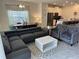 Open-concept living room with modern gray sectional, chairs, and a stylish white coffee table at 8934 Stinger Dr, Davenport, FL 33896