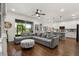 Open-concept living room with a gray sectional sofa, wood-look flooring, and a view of the kitchen and backyard at 922 Grazie Loop, Davenport, FL 33837