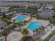 Aerial view of the community pools with a splash pad, lounge chairs, and palm trees at 13232 Alderley Dr, Orlando, FL 32832