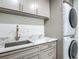 Laundry room features modern cabinets, marble countertop, sink, and stacked washer and dryer at 13735 Sw 73Rd St, Ocala, FL 34481