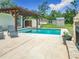Backyard featuring a clean, sparkling pool, patio, wooden pergola, and fireplace, perfect for outdoor living at 13735 Sw 73Rd St, Ocala, FL 34481
