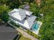 An aerial shot shows a property's pool, metal roof, and landscaping, surrounded by mature trees and privacy fence at 1820 Glencoe Rd, Winter Park, FL 32789