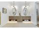 Spa-like bathroom featuring a double vanity with marble countertops, wooden cabinetry, and stylish mirrors at 1820 Glencoe Rd, Winter Park, FL 32789