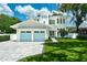Stunning two-story home with a well-manicured lawn, blue garage doors, and elegant architectural details at 1820 Glencoe Rd, Winter Park, FL 32789