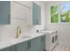 Bright laundry room features blue cabinets, white countertops, brass faucet, and modern washer and dryer at 1820 Glencoe Rd, Winter Park, FL 32789