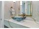 Close up of a designer powder room with a blue glass vessel sink on a marble countertop at 1820 Glencoe Rd, Winter Park, FL 32789