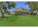 Inviting exterior features a columned front porch, lush lawn, mature trees, and manicured landscaping at 19554 Spring Oak Dr, Eustis, FL 32736