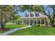 Inviting single-Gathering home featuring a well-manicured lawn, inviting porch, and mature trees with a clear sky at 19554 Spring Oak Dr, Eustis, FL 32736