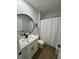 Bright bathroom featuring a round mirror, modern vanity, and a shower with white curtain at 1982 King Ranch St, Kissimmee, FL 34744