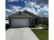 Charming single-story home featuring a two-car garage, well-manicured lawn, and inviting front entrance at 1982 King Ranch St, Kissimmee, FL 34744