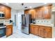 Functional kitchen with stainless steel refrigerator, wooden cabinetry, and tile backsplash at 205 Stevenage Dr, Longwood, FL 32779