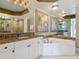 Bathroom vanity and large bathtub with mirrors, lighting fixtures and art at 2055 S Atlantic Ave # 1410, Daytona Beach Shores, FL 32118