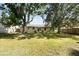 Well-manicured lawn with mature trees in backyard and patio furniture on small paver patio at 303 Mariana Way, Kissimmee, FL 34758