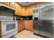 Traditional kitchen with wooden cabinetry, stainless steel refrigerator, and white stove at 303 Mariana Way, Kissimmee, FL 34758