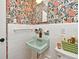 Bathroom featuring vintage-style with a charming green sink and colorful floral wallpaper at 3519 Amigos Ave, Orlando, FL 32808