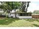 Exterior view of the home and screened in patio surrounded by lush greenery and shade trees at 3519 Amigos Ave, Orlando, FL 32808