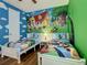 Whimsical bedroom with colorful Disney-themed mural, two twin beds and a white door with cloud accents at 370 Pendant Ct, Kissimmee, FL 34747