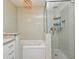 Modern bathroom features white tile walls, a glass shower, and a separate bathtub with a decorative chandelier at 448 Stonewood Ln, Maitland, FL 32751