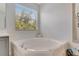A stylish bathtub features a serene view from the window, and a neutral toned basket to hold your bathing accessories at 486 Shirley Dr, Apopka, FL 32712