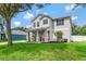 Charming two-story home with a well-manicured lawn, blue shutters, and inviting front porch with comfortable seating at 486 Shirley Dr, Apopka, FL 32712