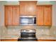 Kitchen showcasing wooden cabinets, granite countertops, stainless steel microwave, and a modern black electric stovetop at 486 Shirley Dr, Apopka, FL 32712