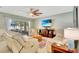The bright living room features tile flooring, a ceiling fan, a large TV, and comfortable seating at 486 Shirley Dr, Apopka, FL 32712