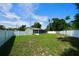 Fenced backyard with green lawn, mature trees, and screened patio at 5472 E Grant St, Orlando, FL 32812
