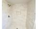 New shower featuring travertine tile, stylish shower head, and recessed storage at 5472 E Grant St, Orlando, FL 32812