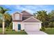 Charming two-story home boasts a welcoming blue front door, well-manicured lawn, and attached two-car garage at 5687 Portico Pl, Kissimmee, FL 34758