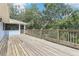 Wide wooden deck with access to a screened-in porch, offering scenic views of the surrounding lush landscape at 5836 Spruce Creek Woods Dr, Port Orange, FL 32127